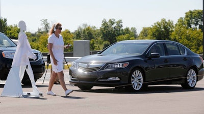 In this July 20, 2015 file photo, a pedestrian crosses in front of a vehicle as part of a demonstration at Mcity, used to test driverless and connected vehicles, on the University of Michigan campus in Ann Arbor, Mich. The U.S. auto industry's home state of Michigan is preparing for the advent of self-driving cars by pushing legislation to allow for public sales and operation _ a significant expansion beyond an existing law that sanctions autonomous vehicles for testing only.