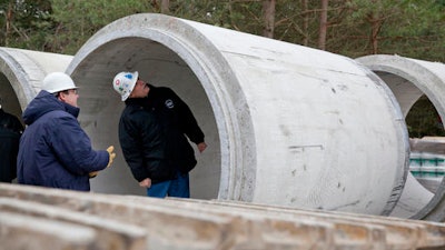 In this Nov. 26, 2013 file photo, Karegnondi Water Authority CEO Jeff Wright, right, and Deputy CEO John O'Brien look inside a pipe that will be part of the Karegnondi Pipeline Project, in Worth Township, Mich. After months of national attention on lead-tainted drinking water in Flint, many are starting to ask questions about the 74-mile pipeline being built from Lake Huron to the struggling former auto manufacturing powerhouse.
