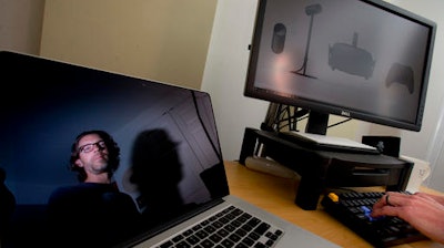 In this Friday, April 22, 2016, photo, Christian Cantrell, a software engineer and science fiction author, poses for a photo at his high-end computer setup that an Oculus Rift camera will go with, at his home in Sterling, Va. Cantrell pre-ordered the device and is still waiting, despite the fact that the gadgets began shipping weeks earlier.