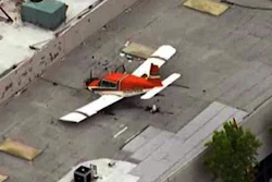 This aerial image made from a video provided by KNBC-TV shows a small plane that crash-landed on the roof of an industrial building in Pomona, Calif., Sunday, May 8, 2016. The FAA said the single-engine plane went down under unknown circumstances.