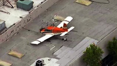 This aerial image made from a video provided by KNBC-TV shows a small plane that crash-landed on the roof of an industrial building in Pomona, Calif., Sunday, May 8, 2016. The FAA said the single-engine plane went down under unknown circumstances.