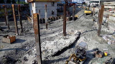 A shipwreck from the 1800s that has been uncovered during construction in the Seaport District is seen to the left of a construction vehicle, bottom, Wednesday, May 25, 2016, in Boston. According to city archaeologist Joe Bagley, it's the first time a shipwreck has been found in this section of Boston. Bagley says it appears the vessel was carrying lime, which was used for masonry and construction.