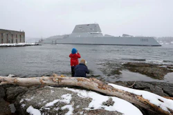 n this March 21, 2016 file photo, Dave Cleaveland and his son, Cody, photograph the USS Zumwalt as it passes Fort Popham at the mouth of the Kennebec River in Phippsburg, Maine, as it heads to sea for final builder trials. The ship is so stealthy that the U.S. Navy resorted to putting reflective material on its halyard to make it visible to mariners during the trials.