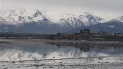 In this Feb. 12, 2016, file photo, the Chugach Mountains and the buildings of downtown Anchorage, Alaska, are reflected in the still waters of Cook Inlet. A national environmental group, the Center for Biological Diversity, has asked the National Marine Fisheries Service to block plans in Cook Inlet by an oil company for hydraulic fracturing, the extraction of oil and gas from rock by injecting high-pressure mixtures of water, sand or gravel and chemicals, because of possible harmful effects on endangered belugas.