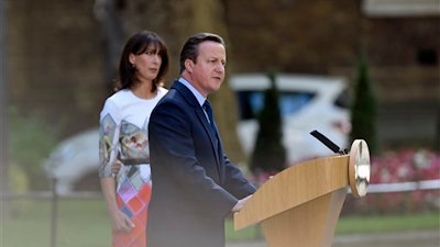 Britain's Prime Minister David Cameron speaks outside 10 Downing Street, London as his wife Samantha looks on Friday, June 24, 2016. Cameron says he will resign by the time of party conference in the fall after Britain voted to leave the European Union after a bitterly divisive referendum campaign, according to tallies of official results Friday.