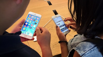 Customers try out Apple iPhone 6S models on display at an Apple Store in Beijing. A Chinese regulator has ordered Apple to stop selling two versions of its iPhone 6 in the city of Beijing after finding it looks too much like a competitor.