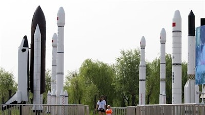 A woman walks with a child as they visit a park with replicas of foreign and domestic space vehicles displayed in Beijing, China. China on Sunday recovered an experimental probe launched aboard a new generation rocket, marking another milestone in its increasingly ambitious space program that envisions a mission to Mars by the end of the decade.