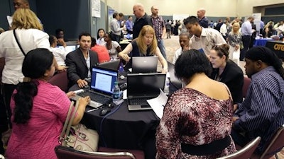 Americans fill out job applications at a job fair.