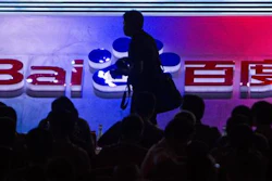 In this Sept. 2, 2011 file photo, a photographer walks past the logo of Baidu Inc., which operates China's dominant search engine, during a technology innovation conference held by the company at China's National Convention Center in Beijing, China. China issued new regulations on Saturday, June 25, 2016 demanding search engines clearly identify paid search results, months after a terminally-ill cancer patient complained that he was misled by the giant search engine Baidu.