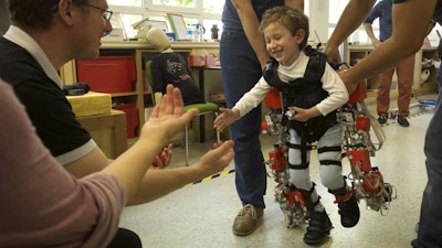 Five-year-old Álvaro, who suffers from spinal muscular atrophy, walks towards his parents during an exoskeleton test.