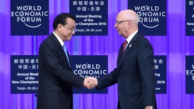 Founder and Executive Chairman of the World Economic Forum Klaus Schwab, right, shakes hands with Chinese Premier Li Keqiang during the World Economic Forum in Tianjin, China Monday, June 27, 2016.