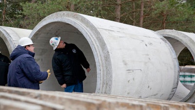 In this Nov. 26, 2013 file photo, Karegnondi Water Authority CEO Jeff Wright, right, and Deputy CEO John O'Brien look inside a pipe that will be part of the Karegnondi Pipeline Project, in Worth Township, Mich. After months of national attention on lead-tainted drinking water in Flint, many are starting to ask questions about the 74-mile pipeline being built from Lake Huron to the struggling former auto manufacturing powerhouse.