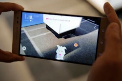 Sam Vang demonstrates playing with a virtual pet on the new Phab2 Pro phone at the Lenovo Tech World event, Thursday, June 9, 2016, in San Francisco. The smartphone will be clever enough to grasp physical surroundings, such as a room's size and the presence of other people, and potentially transform how we interact with e-commerce, education and gaming. Tapping Google's 3-year-old Project Tango, the new phone will use software and sensors to track motions and map building interiors, including the location of doors and windows.