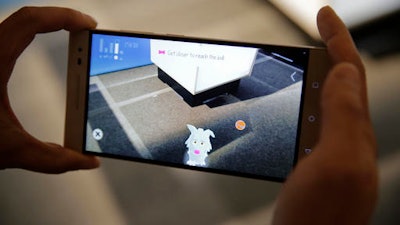 Sam Vang demonstrates playing with a virtual pet on the new Phab2 Pro phone at the Lenovo Tech World event, Thursday, June 9, 2016, in San Francisco. The smartphone will be clever enough to grasp physical surroundings, such as a room's size and the presence of other people, and potentially transform how we interact with e-commerce, education and gaming. Tapping Google's 3-year-old Project Tango, the new phone will use software and sensors to track motions and map building interiors, including the location of doors and windows.