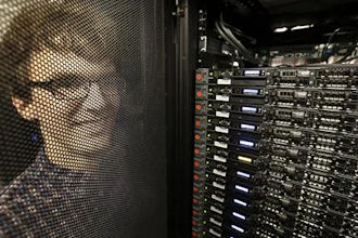 In this Wednesday, June 22, 2016, photo, Massachusetts Institute of Technology researcher Carl Vondrick looks through a protective door while standing next to a computer server cluster, right, on the MIT campus, in Cambridge, Mass. MIT says a computer that binge-watched TV shows such as “The Office,” “Big Bang Theory” and “Desperate Housewives” learned how to predict whether the actors were about to hug, kiss, shake hands or slap high-fives, a breakthrough that eventually could help the next generation of artificial intelligence function less clumsily.