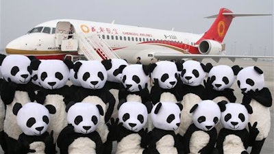 In this photo released by China's Xinhua News Agency, people in panda costumes pose in front of a Chengdu Airlines ARJ21-700 plane before its first commercial flight at Chengdu Shuangliu International Airport in Chengdu in southwestern China's Sichuan Province Tuesday, June 28, 2016. The ARJ21-700, made by the Commercial Aircraft Corporation of China Ltd. (COMAC), is China's first homegrown regional airliner and can seat 78 to 90 passengers depending on its configuration.