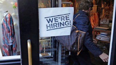 In this Wednesday, May 18, 2016, file photo, a woman passes a 'We're Hiring!' sign while entering a clothing store in the Downtown Crossing of Boston. On Friday, June 3, 2016, the U.S. government issues the May jobs report.