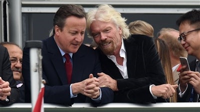 Britain's Prime Minister David Cameron, left, and Virgin boss Richard Branson talk at the Farnborough International Airshow in Farnorough, south England, Monday July 11, 2016. Britain has signed a contract for nine new P-8A Poseidon military aircraft, and Boeing announced Monday a planned expansion for its British operation, as the airshow attracts large international companies to announce their latest plans.