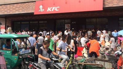 Motorists watch people gather to protest outside a KFC restaurant outlet in Baoying county in east China's Jiangsu province. In an apparent attempt to head off large-scale street demonstrations, Chinese state newspapers have criticized scattered protests against KFC restaurants and other U.S. targets sparked by an international tribunal's ruling that denied Beijing's claim to virtually the entire South China Sea.