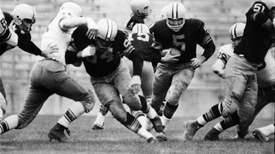 In this Aug. 10, 1959 file photo, Paul Hornung (5) of the Green Bay Packers goes through the line in an inter-squad game in Green Bay, Wis. Pro football Hall of Famer and former Heisman Trophy winner Hornung on Thursday, July 7, 2016, sued equipment manufacturer Riddell Inc., saying their football helmets that he wore during his professional career in the 1950 and ‘60s failed to protect him from brain injury.