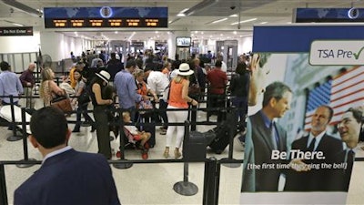 In this Thursday, May 26, 2016, photo, travelers stand in line as they prepare to pass through a Transportation Security Administration checkpoint at Miami International Airport, in Miami. The Transportation Security Administration said Tuesday, July 5, 2016, it will work with American Airlines to speed up security lines. The agency will test CT scanners in Phoenix, and roll out redesigned security lanes this fall in Chicago, Dallas, Los Angeles and Miami.