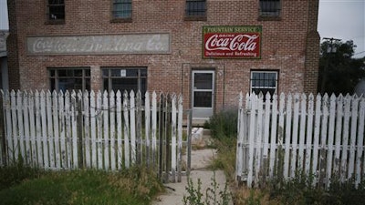 In this July 1, 2016 photo, weeds grow around an old building and picket fence in Rocky Ford, Colo., in Otero County, a rural and increasingly impoverished part of southern Colorado. Two different economic worlds are writ large in this state. It is among those with the greatest economic gap between urban and rural areas, according to an Associated Press review of Economic Innovation Group data.