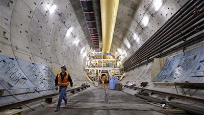 In this photo taken April 25, 2016, a worker walks inside the State Route 99 tunnel under construction in Seattle. The troubled project to replace Seattle's Alaskan Way Viaduct is $223 million over budget, the Washington state Department of Transportation said Thursday, July 21, 2016. The original completion date for the tunnel was the fall of 2015, but the latest estimate for the opening of the double-decker highway project is in 2018.