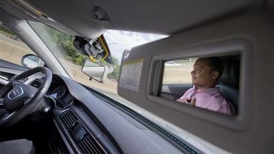 Kaushik Raghu, Senior Staff Engineer at Audi, is reflected in the passenger side visor mirror while demonstrating an Audi self driving vehicle on I-395 expressway in Arlington, Va., Friday, July 15, 2016. Experts say the development of self-driving cars over the coming decade depends on an unreliable assumption by most automakers: that the humans in them will be ready to step in and take control if the car's systems fail.