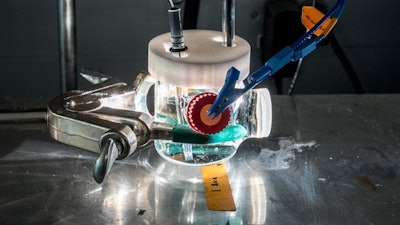 Shown is a photoelectrochemical cell illuminated by a solar simulator. A bismuth vanadate thin-film electrode is being tested in an electrolyte solution to mimic conditions in an artificial photosynthesis device.