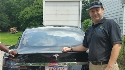 In this 2015 file photo provided by his neighbor, Krista Kitchen, Joshua Brown stands by his new Tesla electric car near his home in Canton, Ohio. Brown died in an accident in Florida on May 7, 2016 in the first fatality from a car using self-driving technology. According to statements by the government and the automaker, his vehicle's cameras didn't make a distinction between the white side of a turning tractor-trailer and the brightly lit sky while failing to automatically activate its brakes.