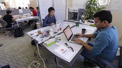 In this Thursday, June 30, 2016 photo, Babson College graduate school alumnus Abhinav Sureka, of Mumbai, India, right, types in his work space at the college in Wellesley, Mass. Some U.S. colleges are starting programs to help their alumni get visas through what critics say is a legal loophole. Foreign grads who want to stay and start a business typically apply for one of the 85,000 H-1B visas that the U.S. gives out each year. But college employees are exempt from that cap, so schools like UMass, Babson and CUNY have launched programs to hire alumni and foreign entrepreneurs and help them grow their businesses here.