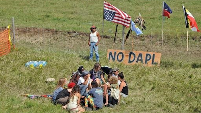 Bill Left Hand, of McLaughlin, S.D., stands next to a sign at the site of a protest Friday, Aug. 12, 2016, against construction of the Dakota Access Pipeline that will cross the Missouri River in Morton County. The pipeline would start in North Dakota and pass through South Dakota and Iowa before ending in Illinois.