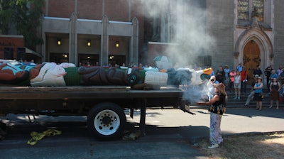 Linda Soriano of the Lummi Nation performs a smudge ceremony at Saint Mark's Episcopal Cathedral in Seattle, fanning smoke from burning sage with eagle feathers onto a totem pole. The 22-foot-tall Lummi Nation totem pole is traveling nearly 5,000 miles across the U.S. and Canada to galvanize opposition to the development of fossil fuel infrastructure, particularly around sea ports in Oregon and Washington.