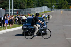 In this July 20, 2015 file photo, a cyclist crosses in front of a vehicle as part of a demonstration at Mcity on the University of Michigan campus in Ann Arbor, Mich. Automakers say cars that wirelessly talk to each other are finally ready for the road. The cars hold the potential to dramatically reduce traffic deaths, improve the safety of self-driving cars and someday maybe even help solve traffic jams. Government and industry have spent more than a decade and more than $1 billion researching and testing the technology, known as vehicle-to-vehicle communications, or V2V.