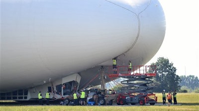 The Airlander 10, is examined as it sits on the ground after a rough landing at Cardington airfield England following its second test flight on Wednesday Aug. 24, 2016. The developer of the world's largest aircraft says the blimp-shaped airship 'sustained damage' after it made a bumpy landing on its second test flight . Hybrid Air Vehicles says it is trying to figure out what caused the rough landing of the 302-foot (92-meter) Airlander 10 during its flight Wednesday in Bedfordshire, north of London.