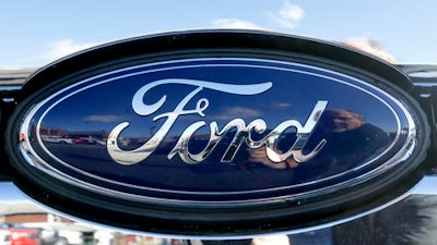 This Thursday, Nov. 19, 2015, file photo, shows the blue Ford oval badge in the grill of a pickup truck on the sales lot at Butler County Ford in Butler, Pa. Ford and Chinese search engine company Baidu announced Tuesday, Aug. 16, 2016, they will invest $75 million each in Velodyne, a company that makes laser sensors that help guide self-driving cars.