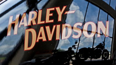 In this July 20, 2010 file photo, motorcycles are reflected in a gas tank at a Harley Davidson dealer in New Berlin, Wis. Harley-Davidson has agreed to pay $15 million to settle a complaint filed by federal environmental officials over racing tuners that caused its motorcycles to emit higher than allowed levels of air pollution.