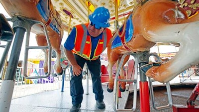 In this Tuesday, Oct. 6, 2015 file photo, amusement device inspector Avery Wheelock inspects the safety pins on a children's merry-go-round at the Mississippi State Fair in Jackson, Miss. In some parts of the U.S., the thrill rides that hurl kids upside down, whirl them around or send them shooting down slides are checked out by state inspectors before customers climb on. But in other places, they are not required to get the once-over.