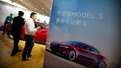 In this April 25, 2016, file photo, visitors look at a Tesla Model S electric car on display at the Beijing International Automotive Exhibition in Beijing. Tesla said August 15, 2016, that the removal of the term autopilot from its website for China was a mistake and the term is being restored.