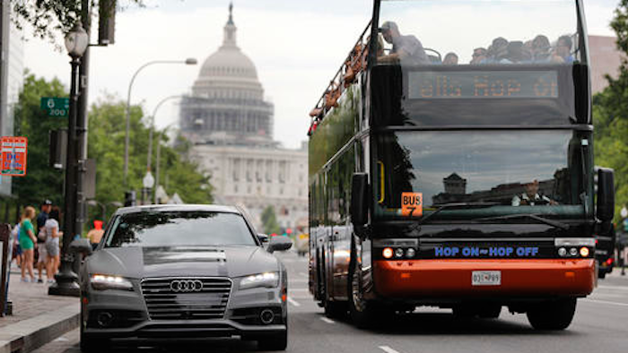 In this July 15, 2016, photo, a double decker tour bus drives by an Audi self driving vehicle parked on Pennsylvania Avenue, near the Capitol in Washington. The federal government should be in charge of regulating self-driving cars rather than states since the vehicles are essentially controlled by software, not people, Obama administration officials said Sept. 19 as they laid out the broad outlines of their plans to help get the transformational technology safely onto the nation’s roadways.
