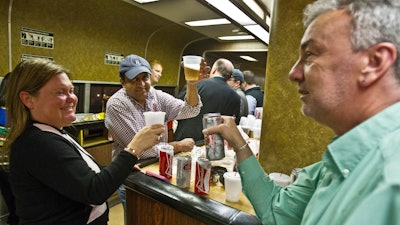 FILE - In a May 8, 2014 file photo, train patrons raise a toast while riding the bar car on the 7:07 p.m. train from Grand Central Terminal in New York to New Haven, CT. The bar cars were retired, but are returning.