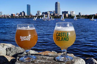 A glass of Samuel Adams Boston Beer Company '80-Miles of Helles' beer, left, and a glass of Castle Island Brewing Company 'Chuck, dry hopped cream ale rest on a rock along the bank of the Charles River. Both beers are made using Charles River water.