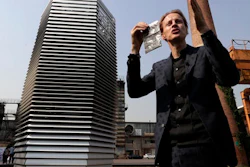 Dutch artist Daan Roosegaarde holds a packet containing smog particles collected by the Smog Free Tower as he presents his machine at D-751art district in Beijing, Thursday, Sept. 29, 2016. In a city where smog routinely blankets the streets and chokes off clean air, a Dutch artist has offered an eccentric solution: a 20-foot metal tower that takes in smog and purifies it like a giant outdoor vacuum cleaner.