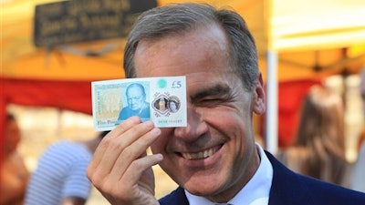 Bank of England Governor Mark Carney holds a new plastic £5 note as he visits Whitecross Street market in London, Tuesday, Sept. 13, 2016. The polymer note is said by the Bank of England to be cleaner, safer and stronger than paper notes, lasting around five years longer.