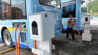 In this July 15, 2016, photo, a driver charges an electric bus made by King Long United Automotive Industry at a terminal in Lin'an city in eastern China's Zhejiang Province. China's electric vehicle industry, a flagship for Beijing's technology ambitions, has been rocked by scandal after five companies were caught collecting millions of dollars in subsidies for buses they never made.