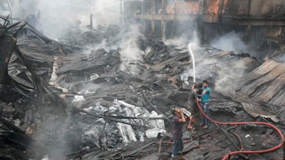 Bangladeshi people and firefighters work to put out a fire at a packaging factory in the Tongi industrial area, outside Dhaka, Bangladesh, Sunday, Sept. 11, 2016. A boiler exploded and triggered the fire at the five-story Tampaco Foils Ltd. factory near Bangladesh's capital on Saturday.