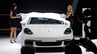 Models remove a cover to unveil the new Porsche Panamera at the Paris Auto Show in Paris, France, Thursday, Sept. 29, 2016. Many major automakers are finding the Paris auto show, held in a city whose mayor wants to ban diesels to reduce pollution, as a fine place to show off new zero-emission electric cars.