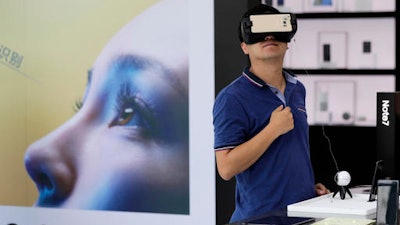 In this Wednesday, Sept. 7, 2016, file photo, a man tries out the Samsung VR using their latest Galaxy Note 7 smartphone at a roadshow outside a shopping mall in Beijing. Two Samsung Galaxy Note 7 smartphones reportedly have caught fire in China in what, if confirmed, would be the first such incidents in the world's largest smartphone market.