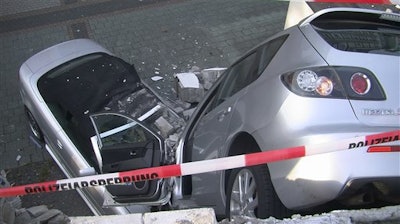 In this Sept. 5, 2016 picture the crash scene in a car park in Bottrop, Germany. An 80-year-old woman took an unintended short cut as she tried to drive her car , right, out of a multistory car park in Germany, breaking though the building’s wall and landing on a parked convertible 3 meters (10 feet) below. Police said that neither the driver nor her 85-year-old husband, who was standing next to the car at the time, were hurt in the accident in Bottrop late Monday.