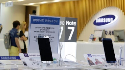 In this Sunday, Sept. 11, 2016 file photo, customers wait for recall of their Samsung Electronics Galaxy Note 7 smartphones as powered-off Galaxy Note 7 smartphones are displayed at the company's service center in Seoul, South Korea. Samsung on Tuesday, Sept. 13, 2016, plans to issue a software update for its recalled Galaxy Note 7 smartphones that will prevent them from overheating by limiting battery recharges to under 60 percent.